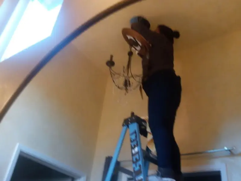 Electrician installing a chandelier in a Scandia residence